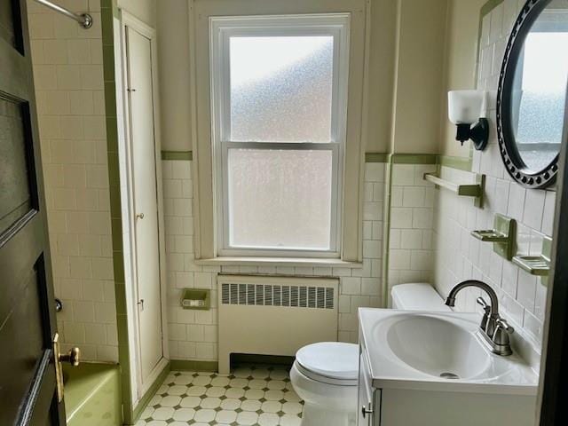 full bathroom featuring vanity, shower / tub combination, toilet, tile walls, and radiator heating unit