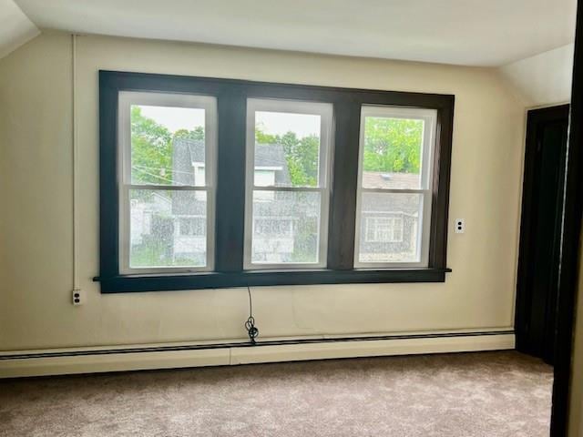 additional living space with carpet flooring, a healthy amount of sunlight, lofted ceiling, and a baseboard heating unit