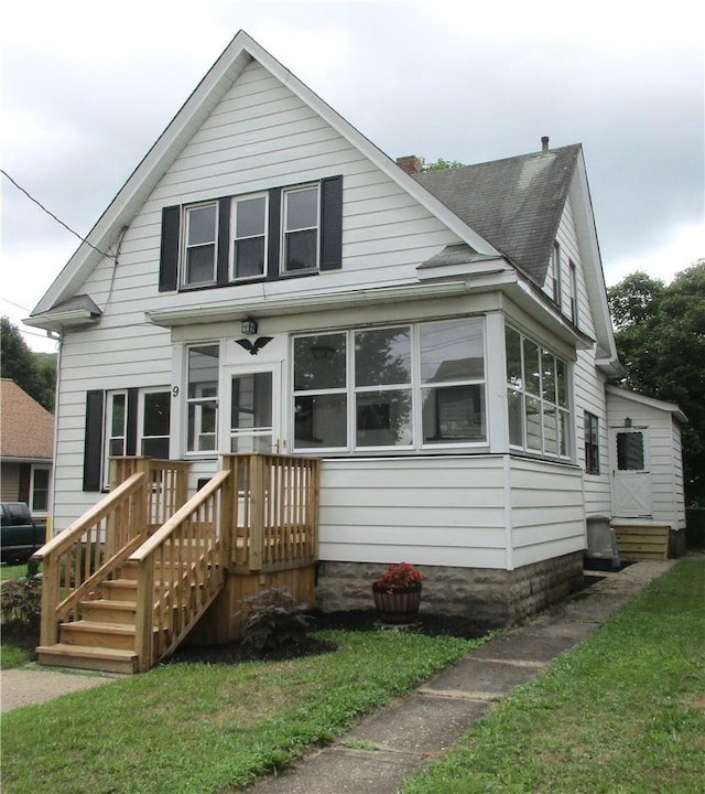 view of front of home with a sunroom and a front yard