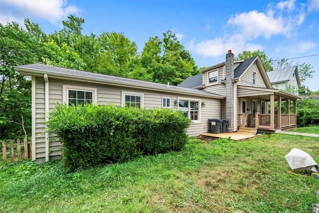 back of property with a yard and covered porch