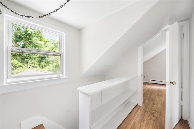 hallway featuring hardwood / wood-style flooring, vaulted ceiling, and a baseboard heating unit