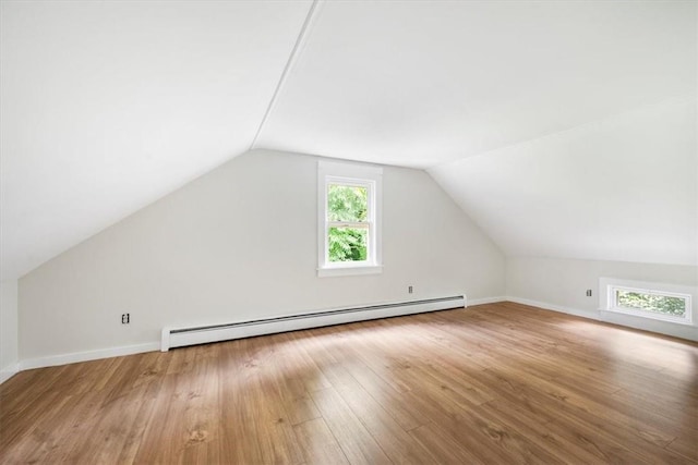 bonus room featuring lofted ceiling, a healthy amount of sunlight, wood-type flooring, and a baseboard heating unit