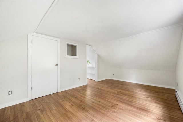 additional living space featuring baseboard heating, light hardwood / wood-style floors, and lofted ceiling