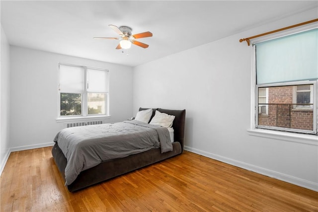 bedroom with ceiling fan, radiator heating unit, and light wood-type flooring