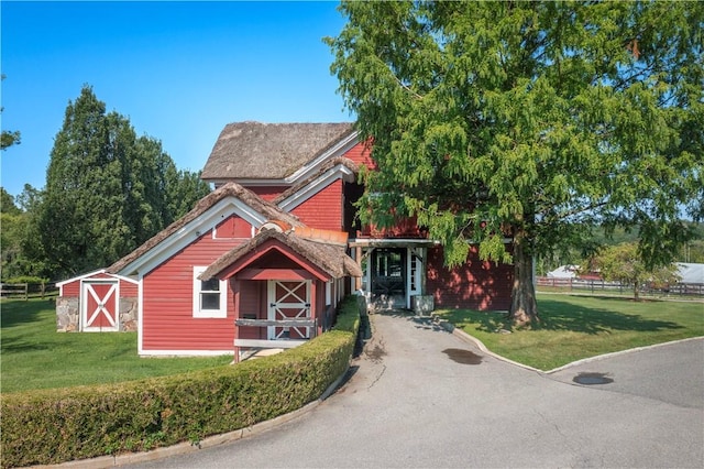 view of front of house featuring an outbuilding and a front lawn