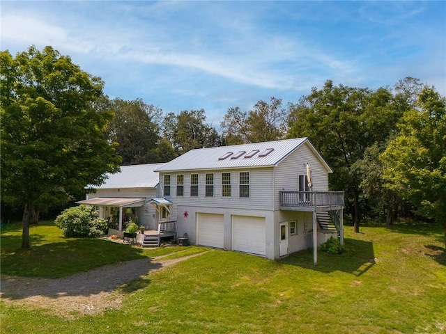 rear view of house with a lawn, a wooden deck, and a garage