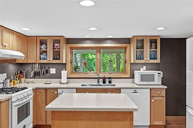 kitchen with light stone counters, sink, a kitchen island, and white appliances