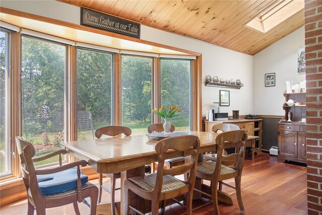 dining space with lofted ceiling with skylight, hardwood / wood-style floors, wooden ceiling, and a baseboard radiator