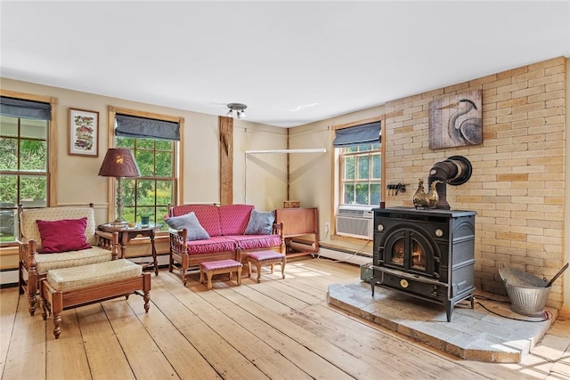 sitting room with light wood-type flooring, a wood stove, and cooling unit