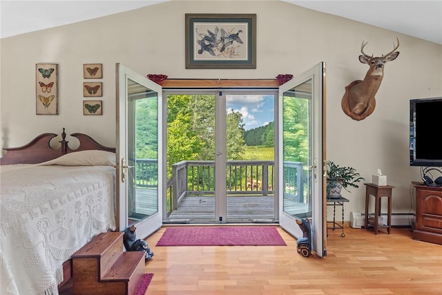 bedroom featuring light wood-type flooring, access to outside, vaulted ceiling, and a baseboard heating unit