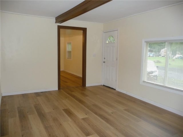 unfurnished room with beam ceiling, light hardwood / wood-style flooring, and ornamental molding