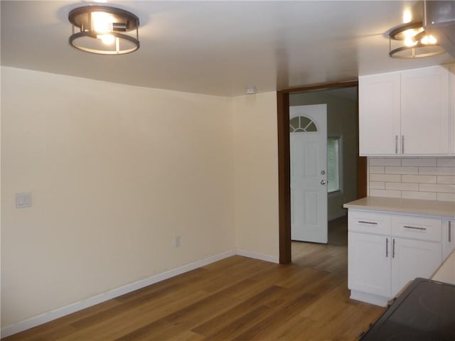 interior space with backsplash, white cabinets, wood-type flooring, and range