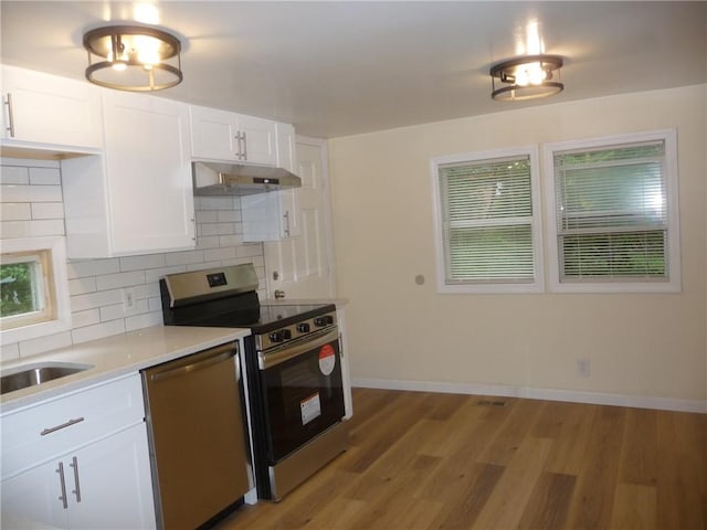 kitchen featuring white cabinets, appliances with stainless steel finishes, backsplash, and light hardwood / wood-style floors