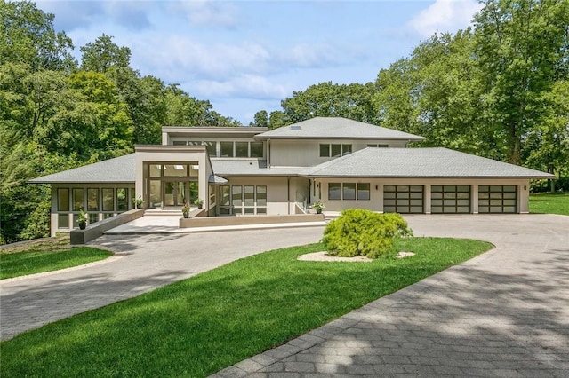 prairie-style home featuring a garage, a front lawn, and a sunroom