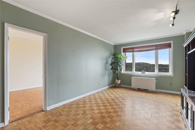 spare room featuring radiator, light parquet floors, and ornamental molding