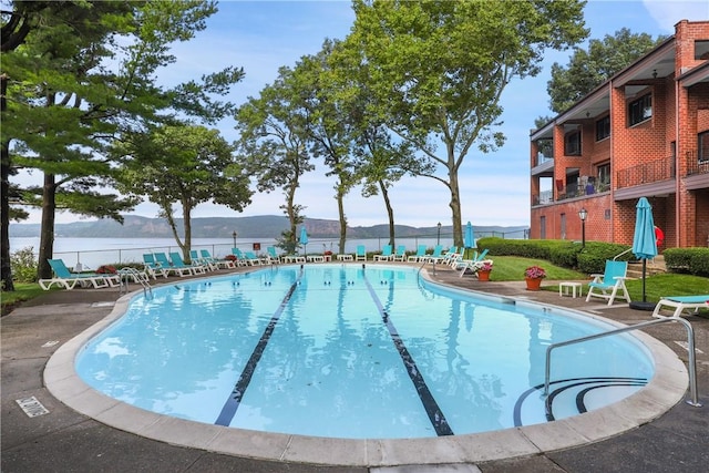 view of pool featuring a patio area and a water view