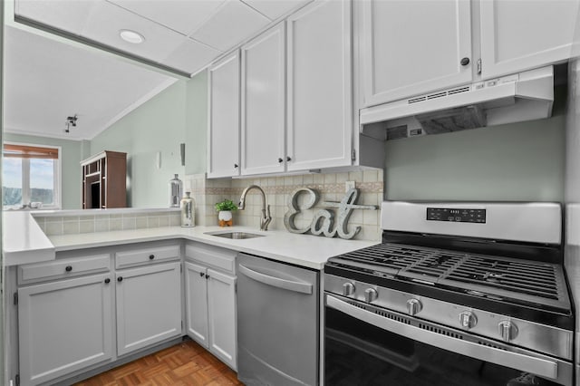 kitchen with appliances with stainless steel finishes, ornamental molding, light parquet floors, sink, and white cabinetry