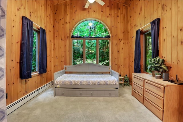 carpeted bedroom with baseboard heating, multiple windows, ceiling fan, and a towering ceiling