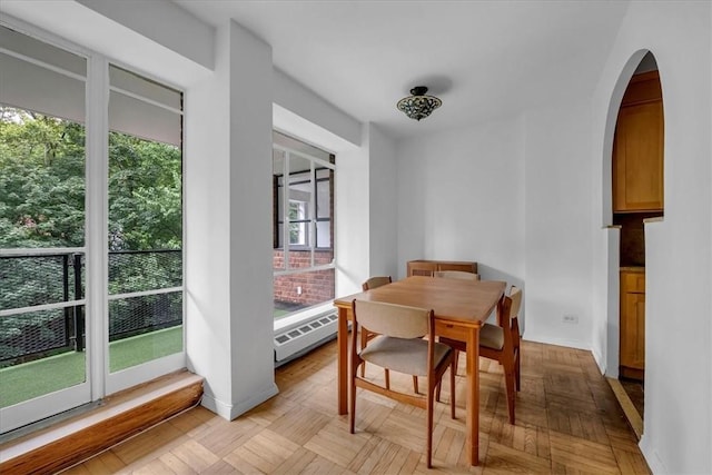 dining space with light parquet floors, baseboard heating, and plenty of natural light