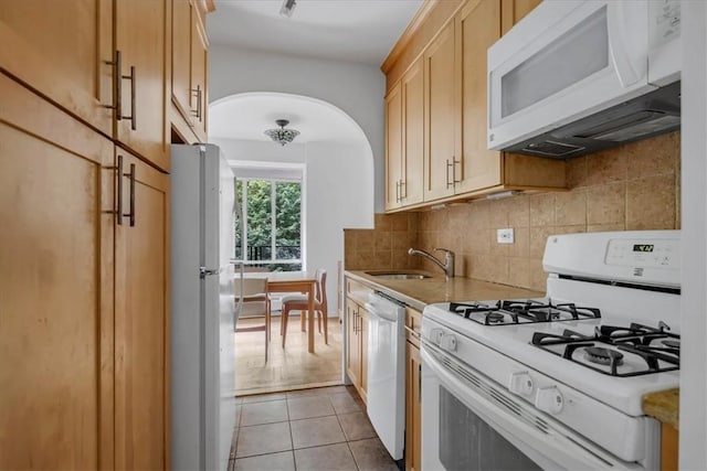 kitchen with sink, tasteful backsplash, white appliances, light brown cabinetry, and light tile patterned floors