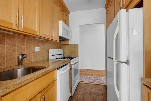 kitchen with white appliances, dark tile patterned flooring, sink, tasteful backsplash, and light stone counters