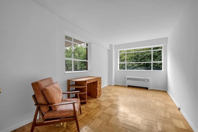 sitting room with a healthy amount of sunlight, radiator heating unit, and light parquet flooring