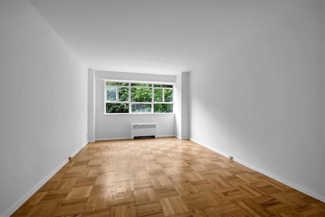 unfurnished room with radiator heating unit and light parquet flooring