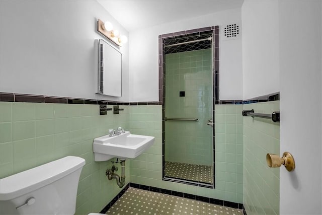 bathroom featuring a tile shower, sink, tile walls, and toilet