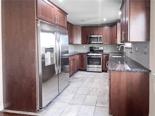 kitchen with dark stone counters, backsplash, sink, and stainless steel appliances