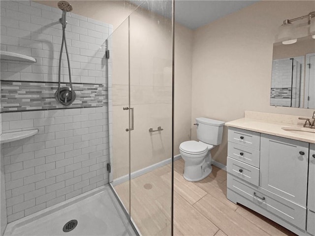 bathroom featuring vanity, toilet, and a shower with door