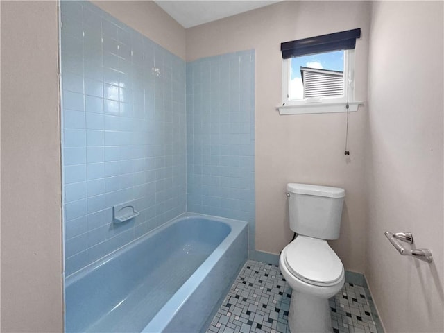 bathroom with tile patterned flooring, tiled shower / bath combo, and toilet