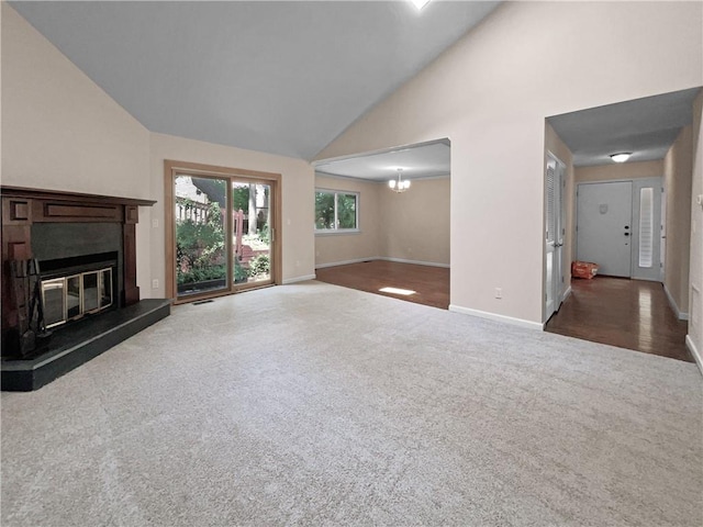 unfurnished living room with high vaulted ceiling, dark carpet, and an inviting chandelier