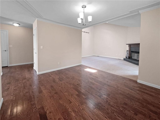 unfurnished living room with crown molding, a chandelier, and dark hardwood / wood-style floors