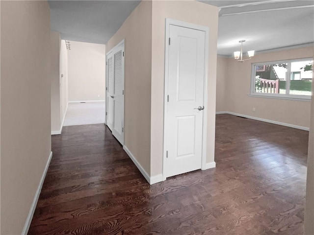 corridor with dark wood-type flooring and an inviting chandelier