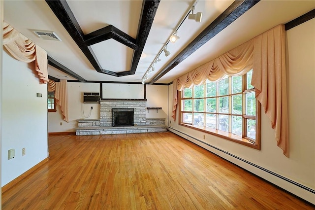 unfurnished living room featuring track lighting, a baseboard heating unit, hardwood / wood-style flooring, beamed ceiling, and a stone fireplace