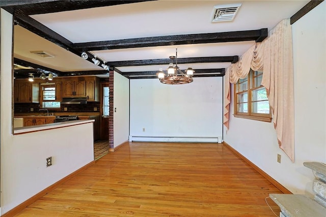 kitchen with a chandelier, a healthy amount of sunlight, baseboard heating, and tasteful backsplash