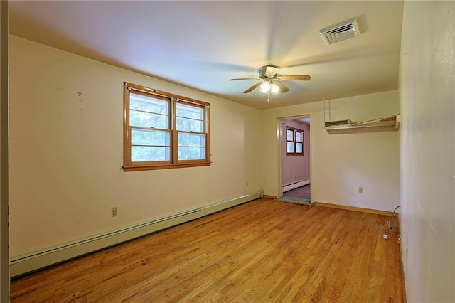 unfurnished room featuring a baseboard radiator, a wealth of natural light, and light hardwood / wood-style floors