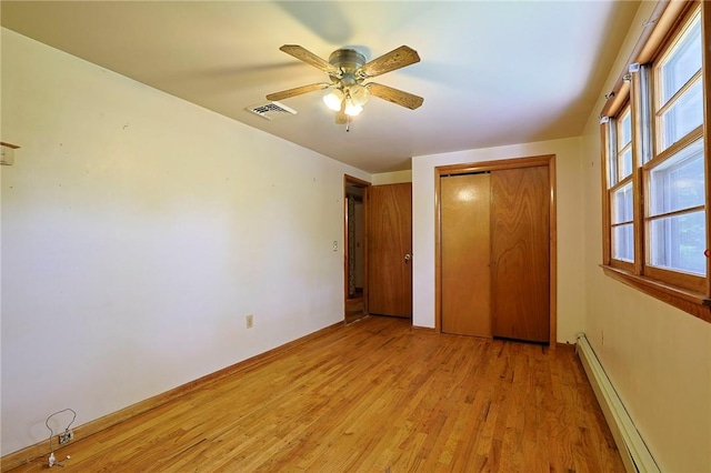 unfurnished bedroom featuring a closet, light hardwood / wood-style flooring, ceiling fan, and a baseboard heating unit