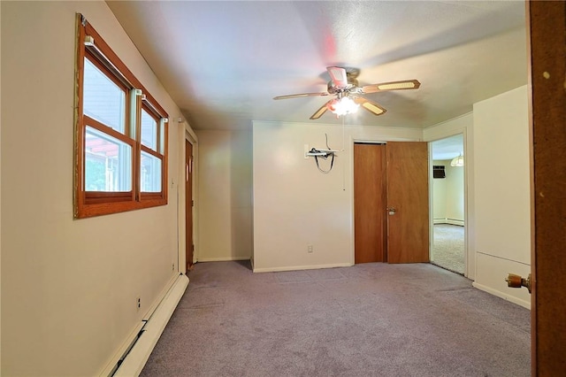 empty room with carpet flooring, ceiling fan, and a baseboard heating unit