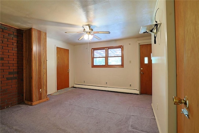 unfurnished room with ceiling fan, a textured ceiling, baseboard heating, light colored carpet, and brick wall