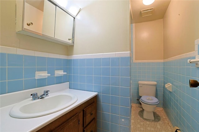 bathroom with tile patterned floors, vanity, toilet, and tile walls