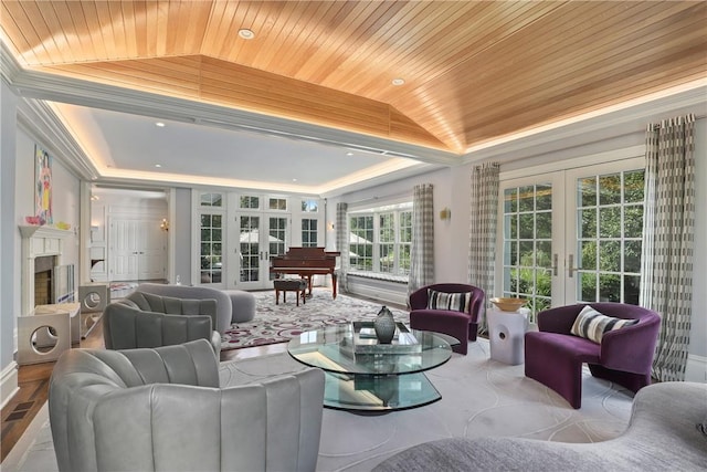 living room featuring a fireplace, ornamental molding, wood ceiling, french doors, and a raised ceiling