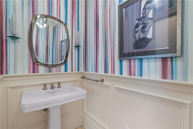 bathroom with a wainscoted wall and wallpapered walls