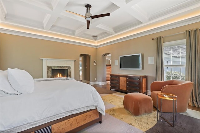 bedroom with beamed ceiling, a ceiling fan, coffered ceiling, arched walkways, and baseboards