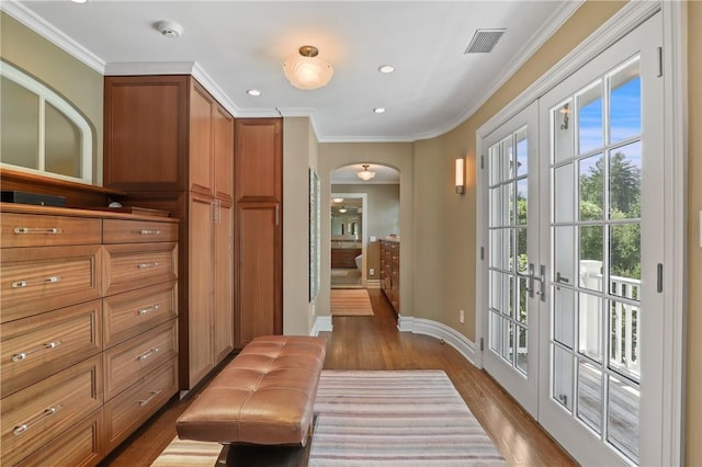 doorway with visible vents, crown molding, baseboards, wood finished floors, and arched walkways