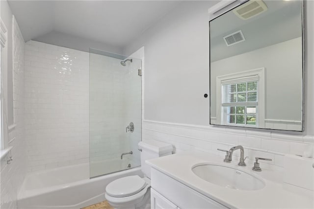 full bath featuring visible vents, toilet, a wainscoted wall, and washtub / shower combination