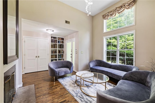 living room with french doors, a towering ceiling, and dark wood-type flooring