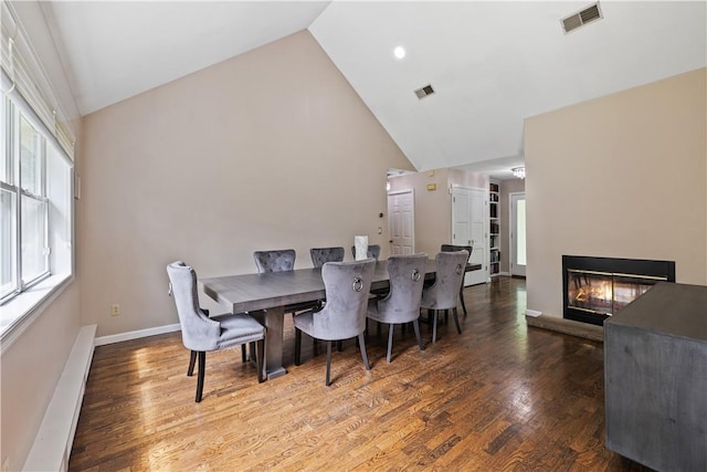 dining space featuring dark hardwood / wood-style flooring and high vaulted ceiling