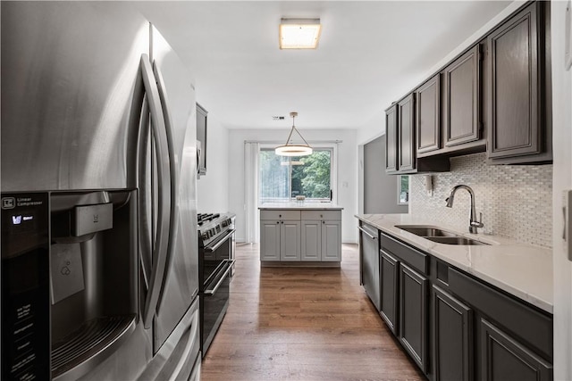 kitchen with decorative backsplash, stainless steel appliances, sink, dark hardwood / wood-style floors, and hanging light fixtures