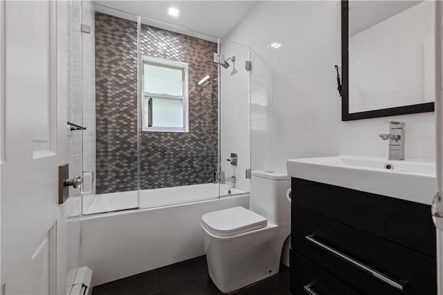 full bathroom with combined bath / shower with glass door, vanity, a baseboard heating unit, tile patterned flooring, and toilet